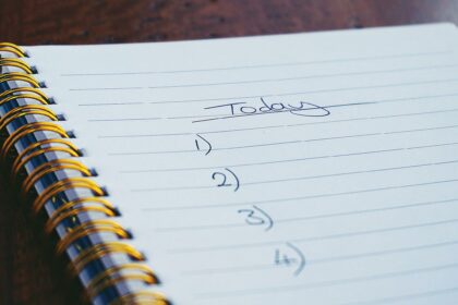 A close-up view of a handwritten to-do list on a spiral notebook with numbers for tasks.